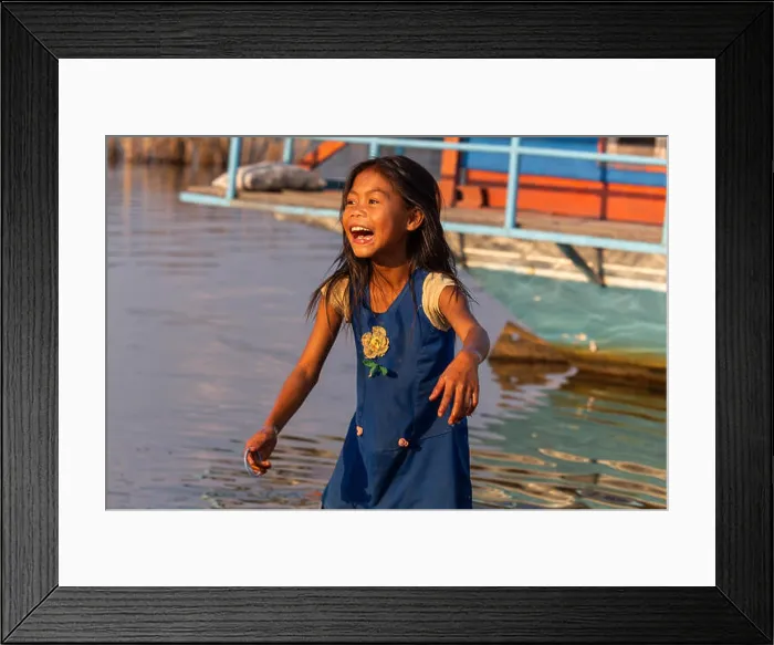 Framed Print : Thakhek, Laos - April 19 2018: Happy girl playing near the water in a remote rural area of Laos Framed Print : Thakhek, Laos - April 19 2018: Happy girl playing near the water in a remote rural area of Laos