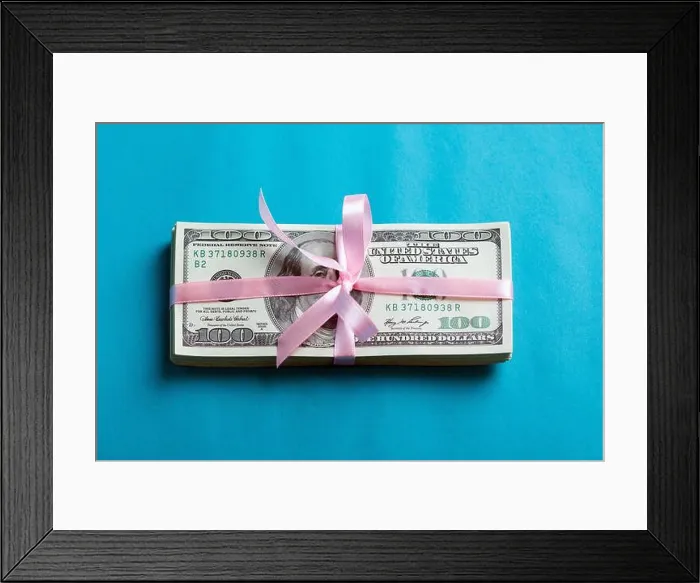 Framed Print : a bundle of dollars tied with a pink ribbon on a blue background Framed Print : a bundle of dollars tied with a pink ribbon on a blue background