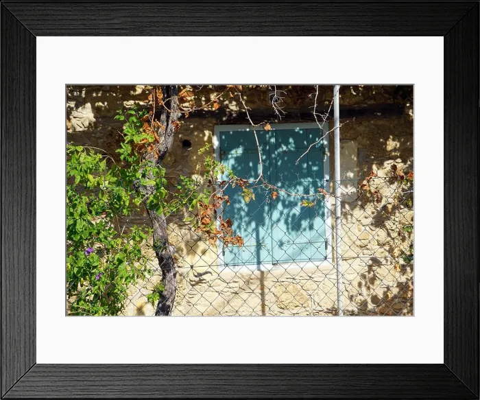 Framed Print : Cyprus, A light beige stone wall with a blue shutter and a white metal fence in front of it Framed Print : Cyprus, A light beige stone wall with a blue shutter and a white metal fence in front of it