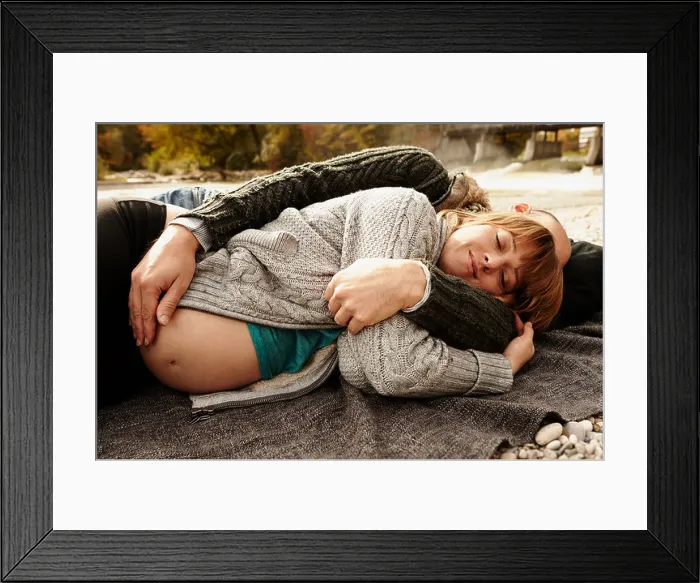 Framed Print : Pregnant woman and partner lying beside river