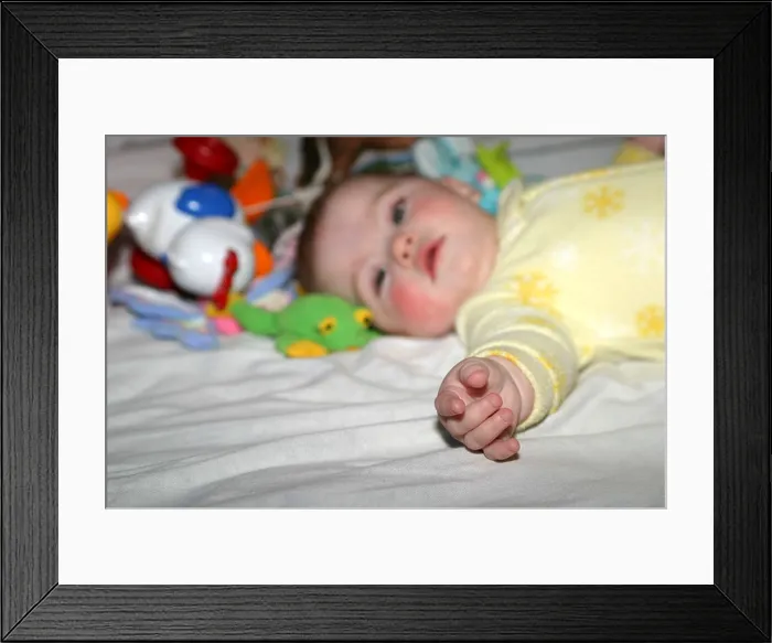 Framed Print : Six month old baby girl in a yellow sleeper surrounded by her toys