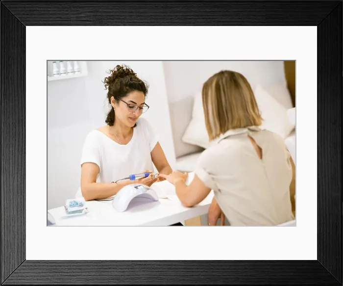 Framed Print : Woman in a nail salon receiving a manicure by a beautician with Framed Print : Woman in a nail salon receiving a manicure by a beautician with