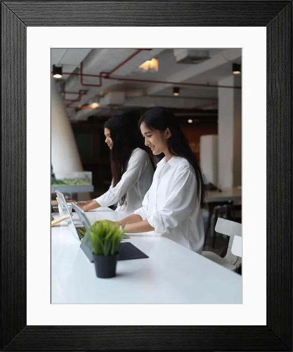 Framed Print : Portrait of female students concentrating on digital tablet while sitting beside each other in co working space Framed Print : Portrait of female students concentrating on digital tablet while sitting beside each other in co working space