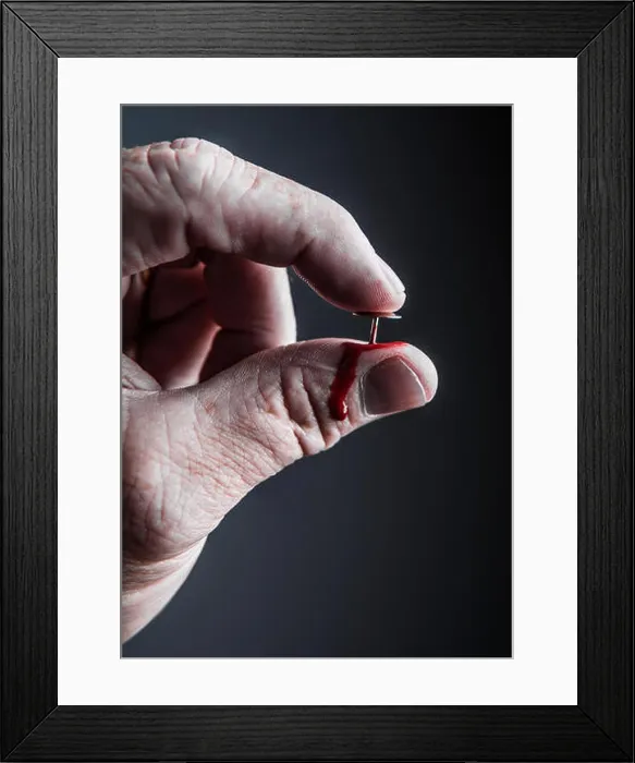 Framed Print : A man's hand pressing a thumbtack into his thumb