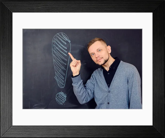 Framed Print : bearded man near a black school board, with an expression showing his hand on an exclamation mark on it
