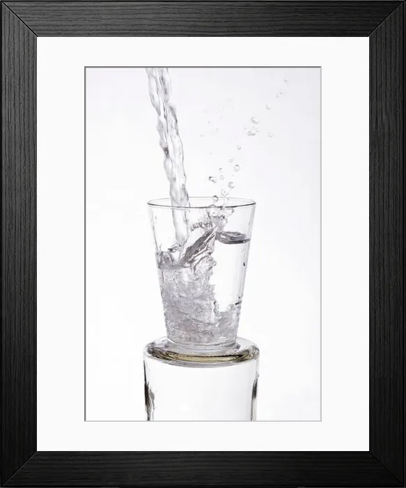 Framed Print : Water vigorously poured overflowing splashing from a glass, on a white background Framed Print : Water vigorously poured overflowing splashing from a glass, on a white background