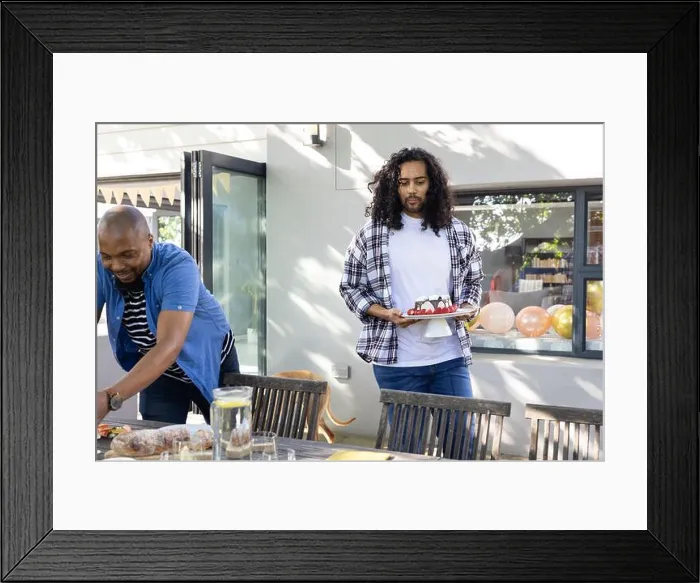 Framed Print : Carrying cake and arranging decorations, friends setting outdoor table for celebration Framed Print : Carrying cake and arranging decorations, friends setting outdoor table for celebration