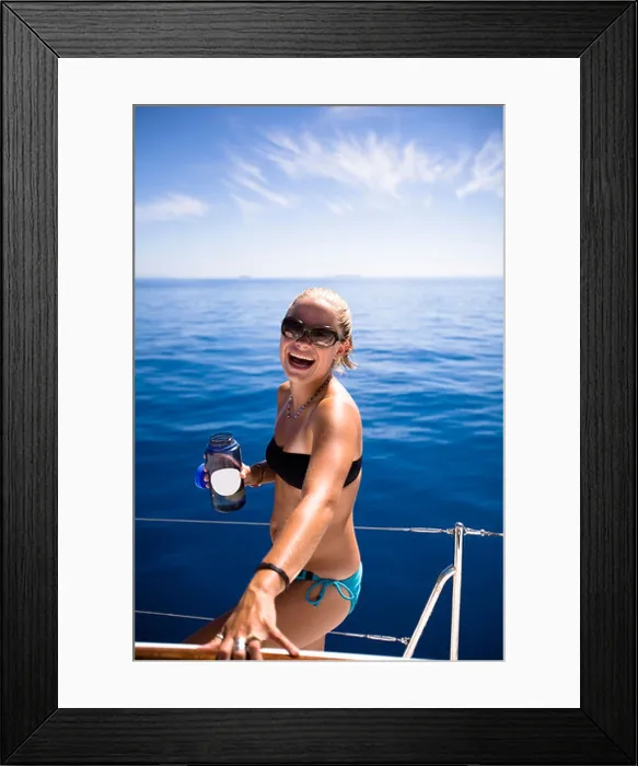 Framed Print : An attractive young woman in a small bikini holding a water bottle laughs while sailing near Namotu, Fiji Framed Print : An attractive young woman in a small bikini holding a water bottle laughs while sailing near Namotu, Fiji
