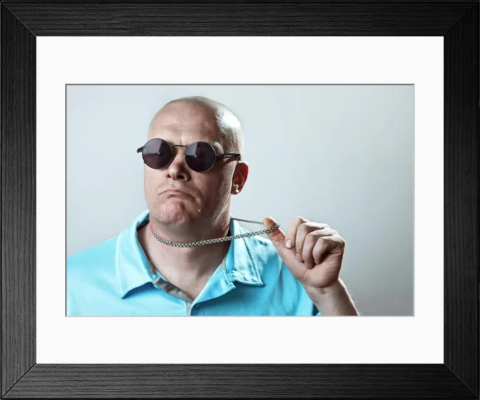 Framed Print : bald brutal man in round glasses and a light t-shirt pulls a silver chain Framed Print : bald brutal man in round glasses and a light t-shirt pulls a silver chain