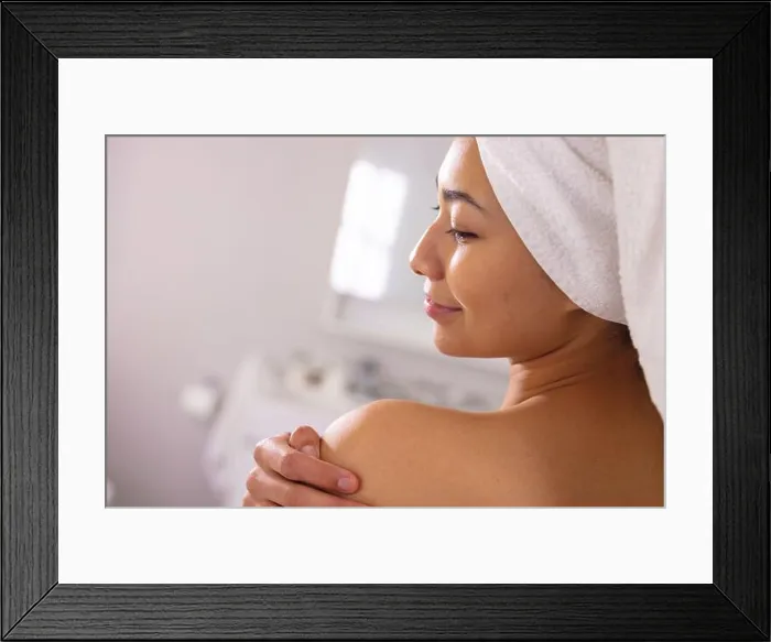 Framed Print : Happy biracial woman wearing towel smiling in bathroom, with copy space
