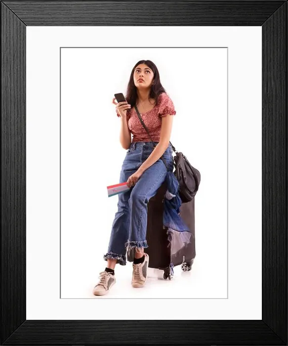 Framed Print : A young woman with an exhausted expression booking an online travel ticket on mobile phone Framed Print : A young woman with an exhausted expression booking an online travel ticket on mobile phone