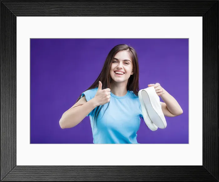 Framed Print : Pretty happy smiling brunette girl dressed in blue t-shirt holding sport footwear sneakers before blue background Framed Print : Pretty happy smiling brunette girl dressed in blue t-shirt holding sport footwear sneakers before blue background