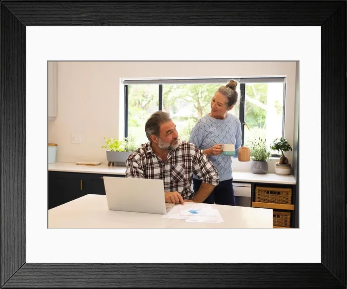 Framed Print : Mature couple enjoying coffee break at home, man using laptop in kitchen Framed Print : Mature couple enjoying coffee break at home, man using laptop in kitchen