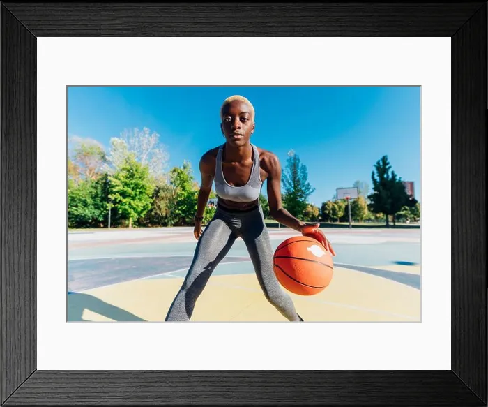 Framed Print : Confident sportswoman playing basketball in sports court Framed Print : Confident sportswoman playing basketball in sports court