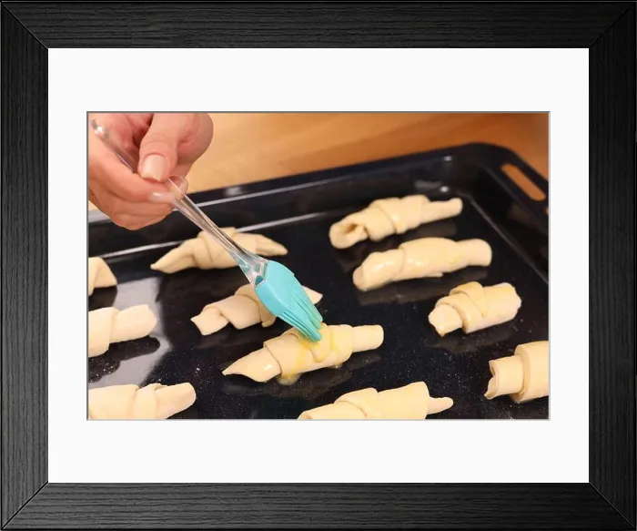 Framed Print : Woman brushing egg wash onto raw croissants at table indoors, closeup Framed Print : Woman brushing egg wash onto raw croissants at table indoors, closeup
