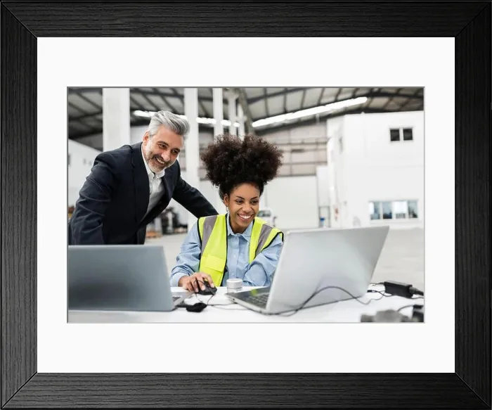 Framed Print : Happy businessman with engineer having video call on laptop in factory Framed Print : Happy businessman with engineer having video call on laptop in factory