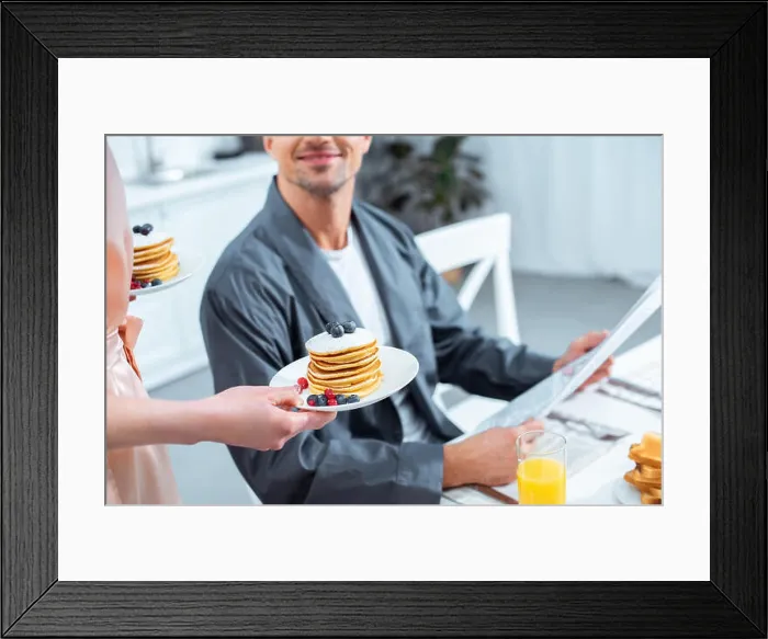 Framed Print : cropped view of woman holding plates with pancakes while man reading newspaper during breakfast in kitchen Framed Print : cropped view of woman holding plates with pancakes while man reading newspaper during breakfast in kitchen