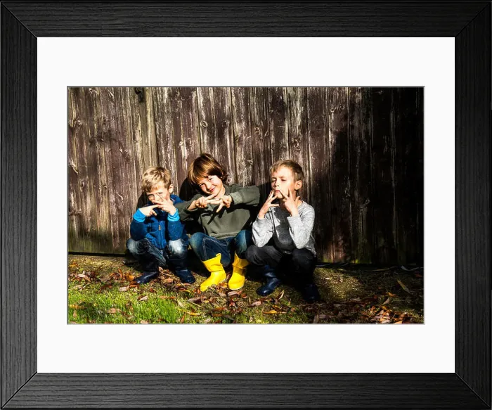 Framed Print : Three boys, outdoors, crouching beside fence, making hand gestures Framed Print : Three boys, outdoors, crouching beside fence, making hand gestures