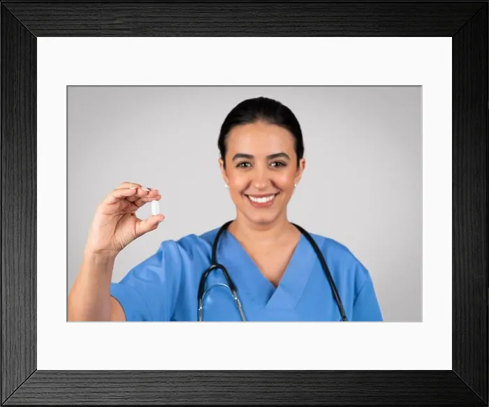 Framed Print : Happy brazilian woman doctor showing capsule pill, vitamins, food supplement in clinic on light grey studio background Framed Print : Happy brazilian woman doctor showing capsule pill, vitamins, food supplement in clinic on light grey studio background