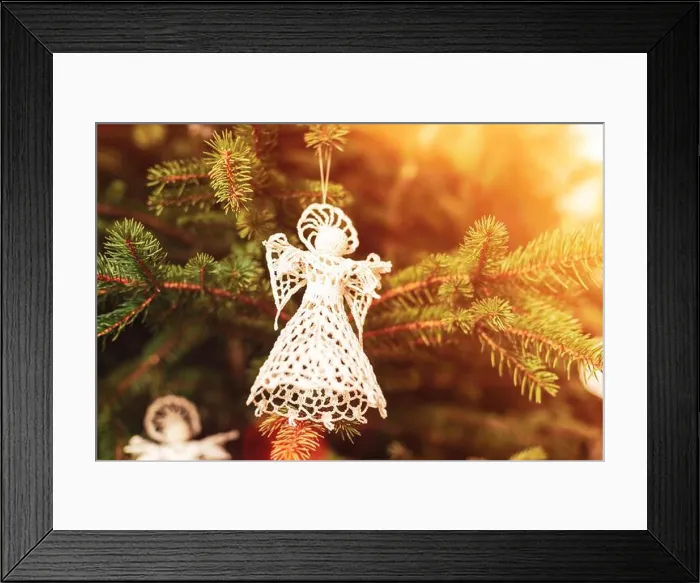 Framed Print : Knitted toy angel on a fir tree in sunlight. Christmas concept. Closeup Framed Print : Knitted toy angel on a fir tree in sunlight. Christmas concept. Closeup