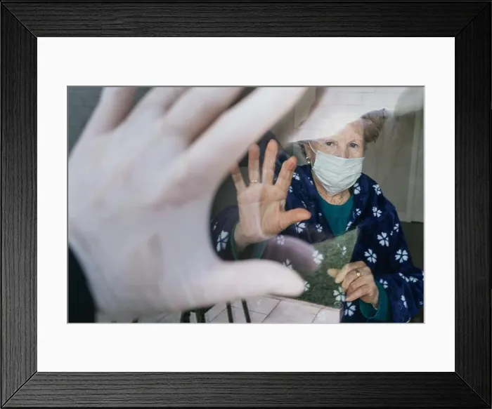Framed Print : Redhead aged female in medical mask waving hand through window to relative while isolating at home Framed Print : Redhead aged female in medical mask waving hand through window to relative while isolating at home