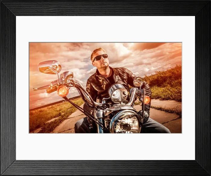 Framed Print : Biker man wearing a leather jacket and sunglasses sitting on his motorcycle looking at the sunset