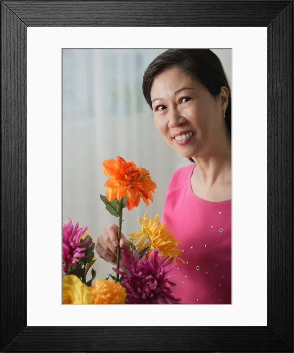Framed Print : Mature woman holding flowers, smiling at camera, portrait Framed Print : Mature woman holding flowers, smiling at camera, portrait
