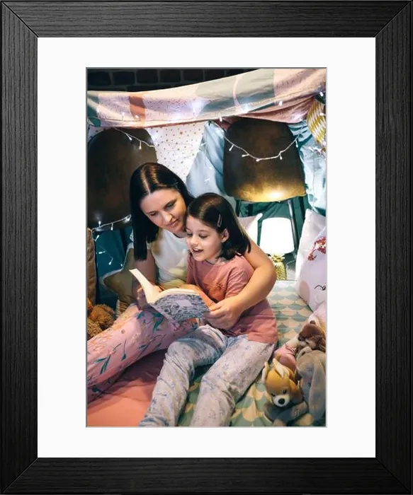 Framed Print : Girl reading with her mother in a makeshift tent at home Framed Print : Girl reading with her mother in a makeshift tent at home