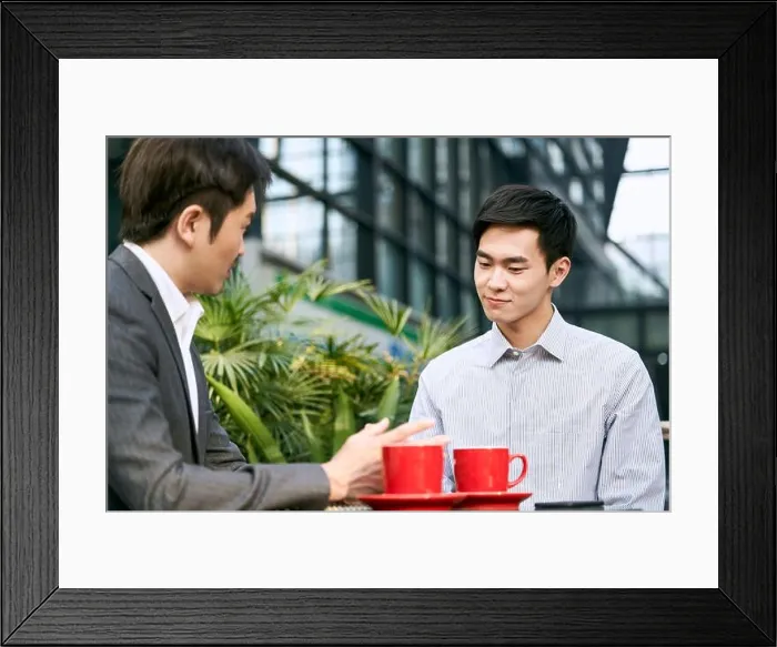 Framed Print : two asian corporate businesspeople discussing business at a outdoor coffee shop Framed Print : two asian corporate businesspeople discussing business at a outdoor coffee shop