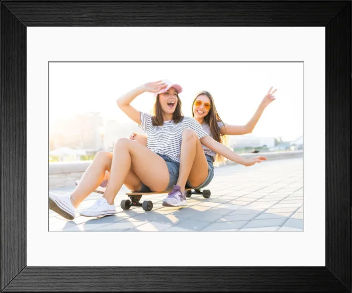 Framed Print : Two smiling young girls having fun while riding on a skateboard at the park Framed Print : Two smiling young girls having fun while riding on a skateboard at the park