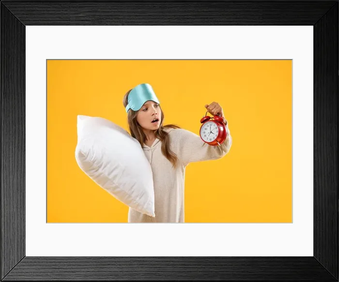 Framed Print : Overslept girl with sleep mask, pillow and alarm clock on orange background