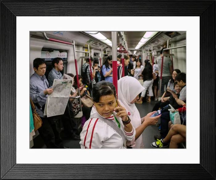 Framed Print : FILE--Two domestic workers use their mobile phones in a subway train in Hong Kong Framed Print : FILE--Two domestic workers use their mobile phones in a subway train in Hong Kong