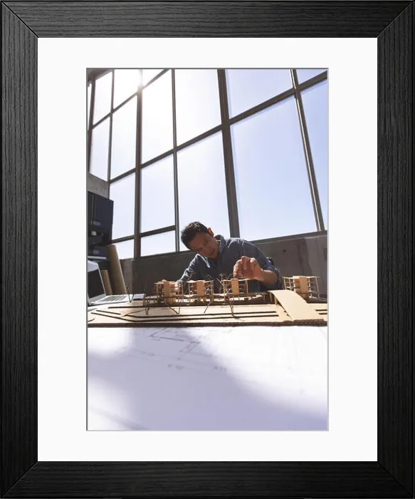 Framed Print : Male architect working on architectural model at desk in a modern office Framed Print : Male architect working on architectural model at desk in a modern office