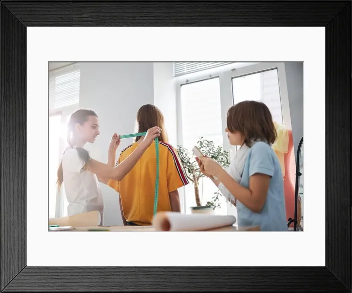 Framed Print : Charming girls taking measurements in sewing workshop Framed Print : Charming girls taking measurements in sewing workshop