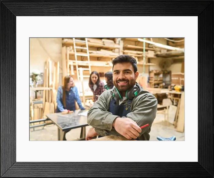 Framed Print : A cheerful young worker stands confidently in a bustling lumberyard workshop Framed Print : A cheerful young worker stands confidently in a bustling lumberyard workshop