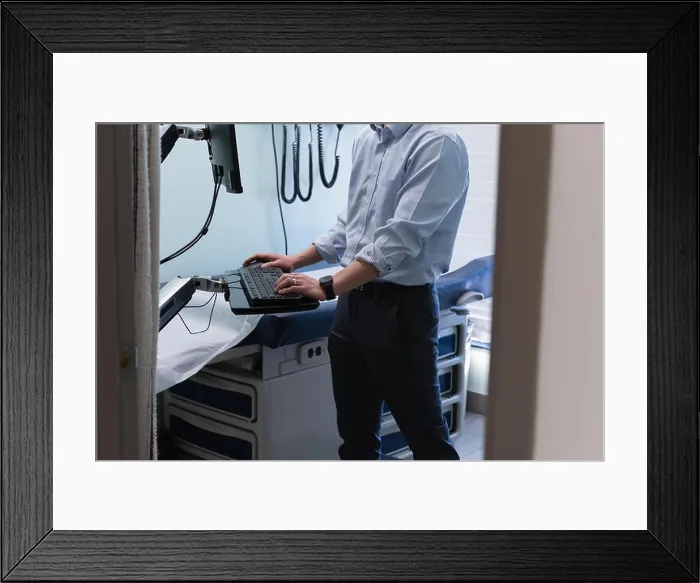 Framed Print : Young asian male doctor working on computer in clinic Framed Print : Young asian male doctor working on computer in clinic