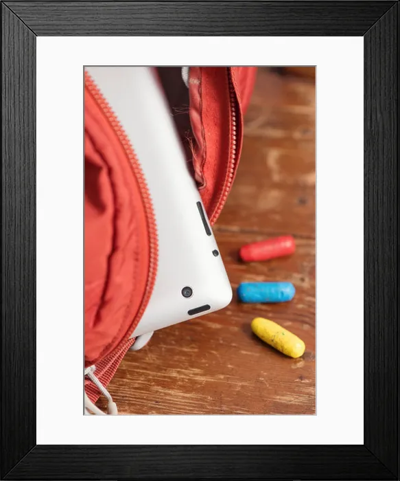 Framed Print : Digital tablet computer in school bag and crayons lying on wooden table Framed Print : Digital tablet computer in school bag and crayons lying on wooden table