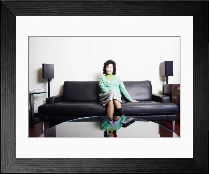 Framed Print : Portrait of a businesswoman sitting on a couch smiling Framed Print : Portrait of a businesswoman sitting on a couch smiling