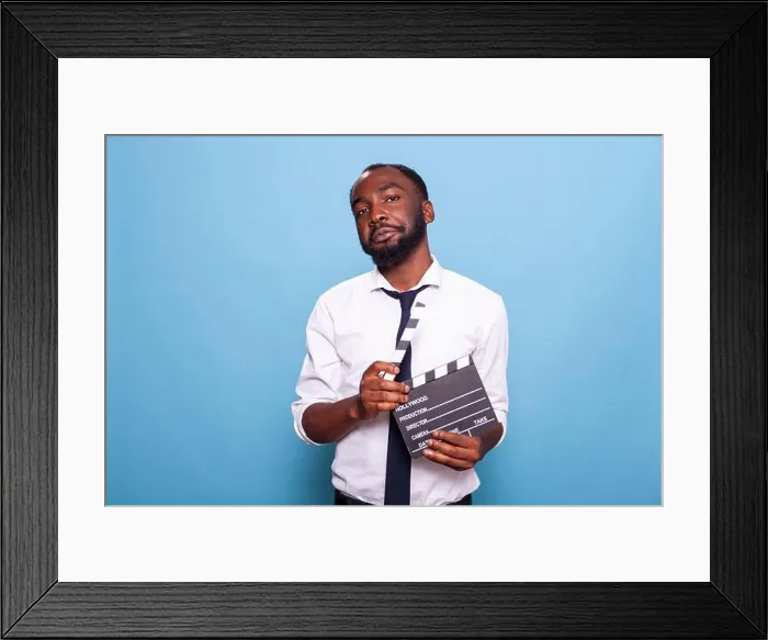 Framed Print : Independent successful filmmaker holding open clapper in hands looking confident with head tilted Framed Print : Independent successful filmmaker holding open clapper in hands looking confident with head tilted