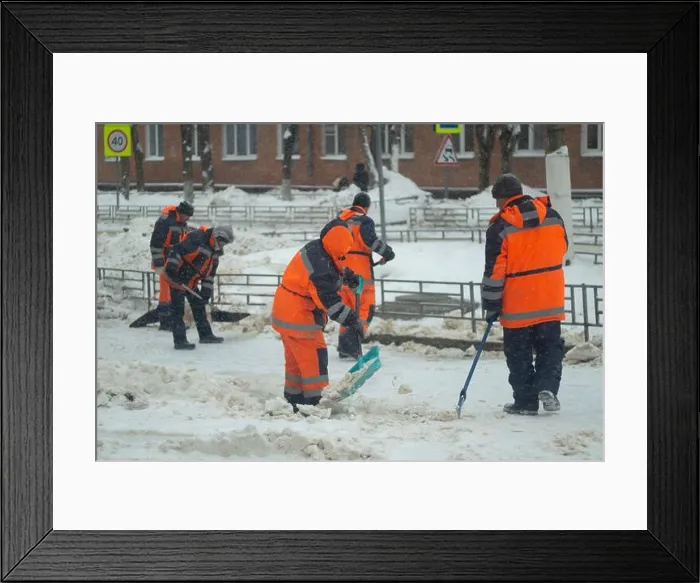 Framed Print : Cleans snow with a shovel. Workers are cleaning the roads after a snowfall Framed Print : Cleans snow with a shovel. Workers are cleaning the roads after a snowfall