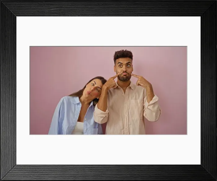 Framed Print : Man and woman making funny faces together against a pink background, showcasing a playful and loving relationship Framed Print : Man and woman making funny faces together against a pink background, showcasing a playful and loving relationship