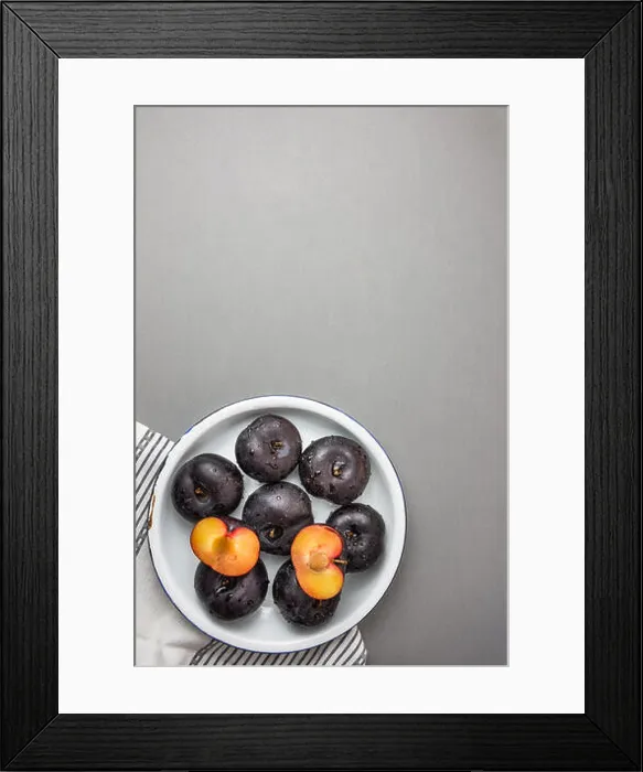 Framed Print : Dark red big plums whole and halved on white vintage enamel plate Framed Print : Dark red big plums whole and halved on white vintage enamel plate