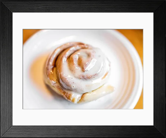 Framed Print : One large cooked baked cinnamon bun roll swirl dessert on white plate with sugar crust on kitchen table Framed Print : One large cooked baked cinnamon bun roll swirl dessert on white plate with sugar crust on kitchen table