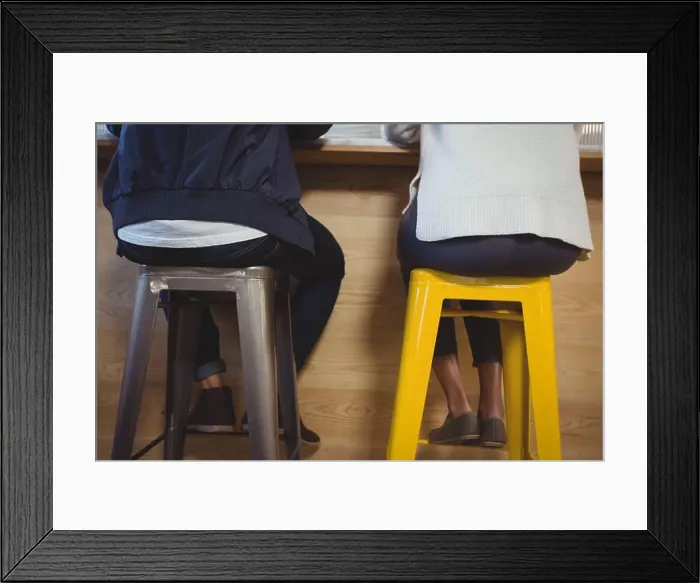 Framed Print : Low section of couple sitting on stools Framed Print : Low section of couple sitting on stools