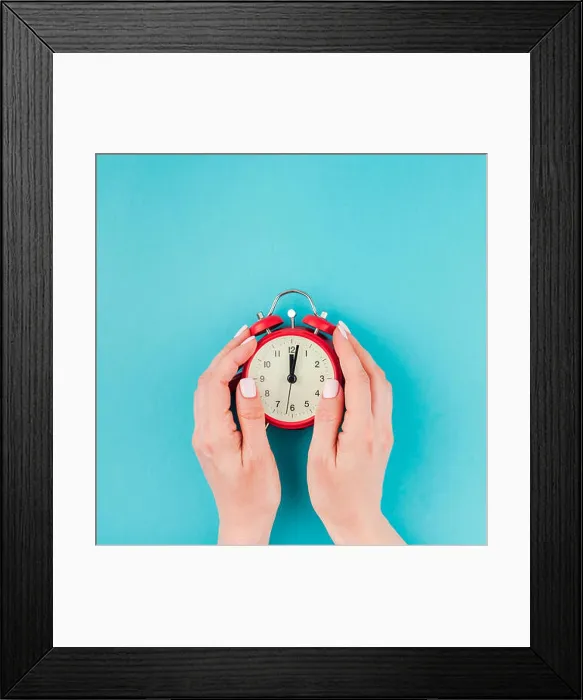 Framed Print : Creative flat lay concept top view of woman hands holding the red vintage alarm clock on square bright blue turquoise