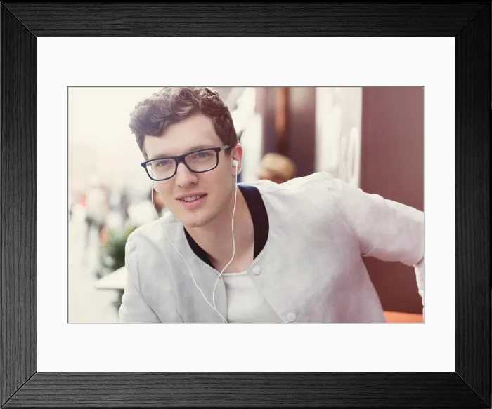 Framed Print : Portrait smiling man with eyeglasses listening to music on headphones Framed Print : Portrait smiling man with eyeglasses listening to music on headphones