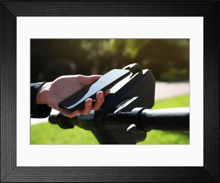 Framed Print : Man using smartphone to pay and unblock rental electric scooter outdoors, closeup