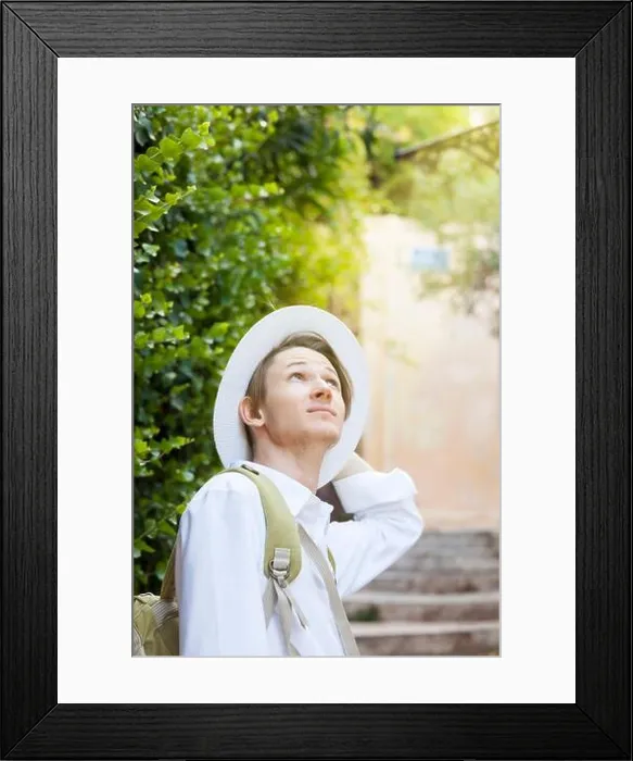 Framed Print : A young Caucasian man in a white hat walks along the street of the old city. Anafiotika. Athens. Greece Framed Print : A young Caucasian man in a white hat walks along the street of the old city. Anafiotika. Athens. Greece