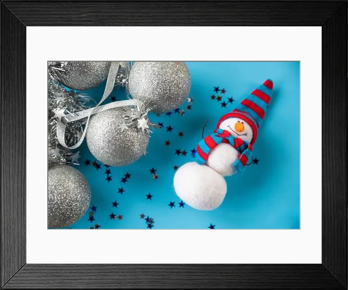 Framed Print : Christmas and New Year needle felted snowman in red blue knitted hat on blue background with silver christmas ornaments Framed Print : Christmas and New Year needle felted snowman in red blue knitted hat on blue background with silver christmas ornaments