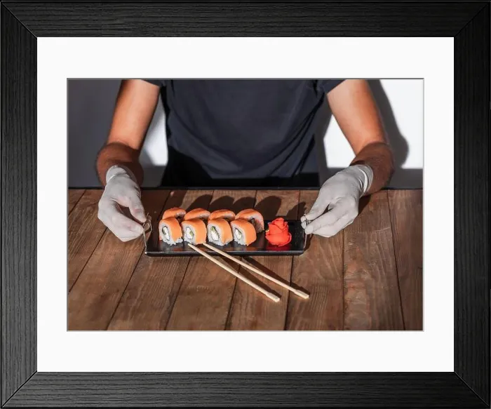 Framed Print : Hands in rubber gloves serve sushi on a wooden table. Sushi menu Framed Print : Hands in rubber gloves serve sushi on a wooden table. Sushi menu